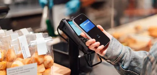 Kobieta w sklepie z ciastkami płacąca kartą wirtualną wgraną do smartfonu