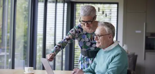 starsze małżeństwo spędzające czas w domu - przed komputerem - wybierające najlepsze konto dla seniorów online