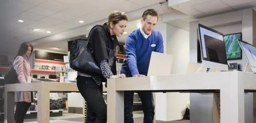 Kobieta w centrum handlowym zaciągająca kredyt ratalny w obecności pracownika sklepu.