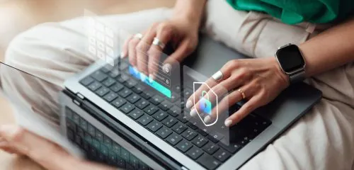 Zbliżenie na dłonie kobiety na klawiaturze laptopa podczas logowania na rachunek bankowy.