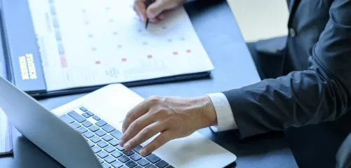 Biznesmen w garniturze sprawdza na stronie banku dostępny okres kredytowania