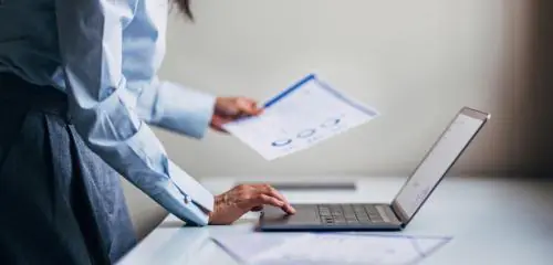 kobieta stojąca przy laptopie i sprawdzająca w raporcie BIK, jaka jest jej wiarygodność kredytowa