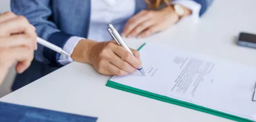 Zbliżenie na dłonie kobiety, która podpisuje umowę kredytową