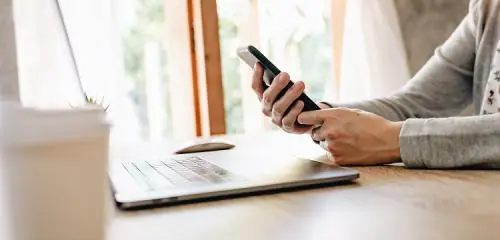 kobieta trzymająca w dłoniach smartfon próbująca zaciągnąć kredyt na telefon
