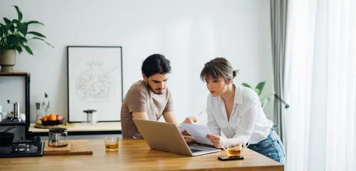 Młode małżeństwo sprawdzające na laptopie czy jest kredyt na podstawie wpływów na konto.