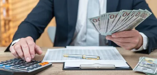 biznesmen z plikiem banknotów, kalkulatorem i umową udzielający pożyczki gotówkowej