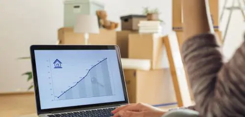 kobieta podczas przeprowadzki sprawdza na laptopie, na jakim poziomie jest stopa referencyjna NBP