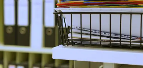Wiele segregatorów i dokumentów stoi na szafie w biurze