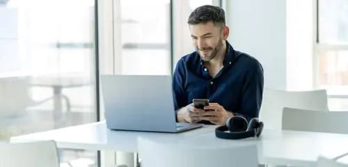 mężczyzna w granatowej koszuli siedzący przed laptopem i sprawdzający, jak zamknąć konto w Santander Bank Polska