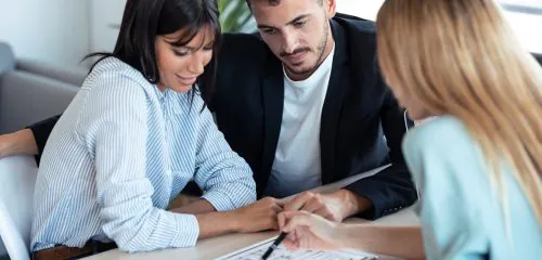 Młoda kobieta podczas spotkania w banku wybiera kredyt hipoteczny z partnerem.