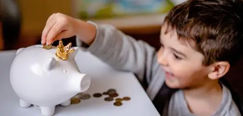 Dziecko wrzuca pieniądze do świnki skarbonki