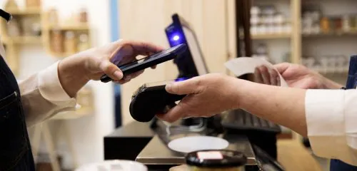 Mężczyzna płaci za zakupy telefonem zbliżeniowo