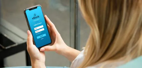 Kobieta loguje sie do banku za pomocą aplikacji mobilnej, żeby zmienić swoje dane