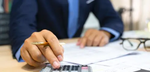 Analityk kredytowy siedzący z kalkulatorem nad dokumentami