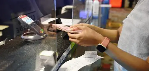 kobieta wymieniająca walutę w kantorze i sprawdzająca na ekranie terminala spread walutowy