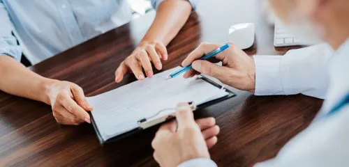 Kobieta podpisuje w banku aneks do umowy o kredyt hipoteczny