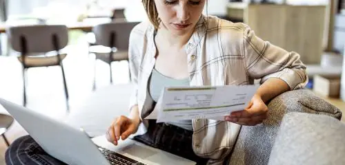 Młoda kobieta sprawdza rachunek i stan swoich finansów
