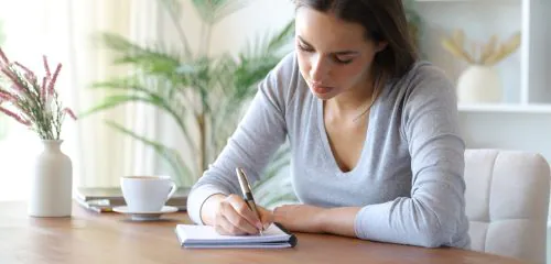 Kobieta zapisuje w notesie adres rozliczeniowy