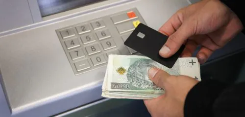 Mężczyzna wpłaca pieniądze na konto za pomocą wpłatomatu
