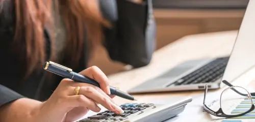 Kobieta liczy na kalkulatorze jaki może wziąć kredyt przy zarobkach 4000 zł netto