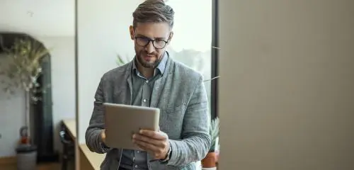 mężczyzna w koszuli i marynarce sprawdzający na tablecie godziny księgowania przelewów w Banku Pocztowym