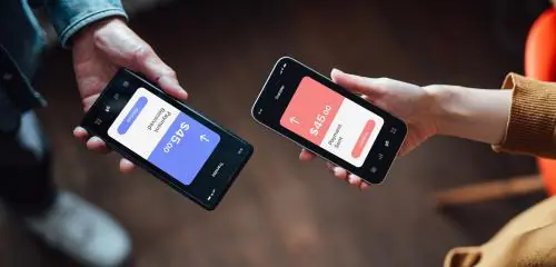 Dwie osoby pokazują sobie smarfony z otwartymi aplikacjami finansowymi