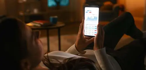 Kobieta leży na kanapie i sprawdza telefonie ile zarabia na lokacie overnight