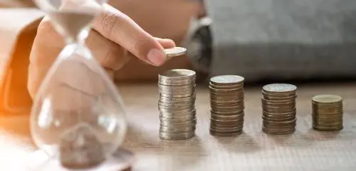 męska dłoń układająca monety w rosnące stosy