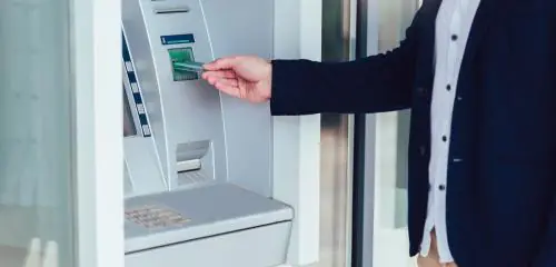 Mężczyzna korzysta z bankomatu za pomocą karty