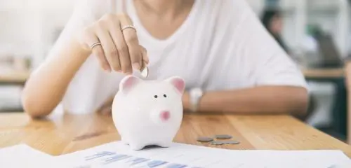 kobieta ze świnką skarbonką planująca swój budżet domowy