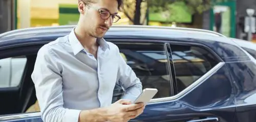 mężczyzna ze smartfonem w dłoni, który sprawdza, jak przenieść aplikację mobilną swojego banku