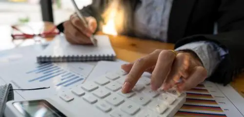 kobieta obliczająca na kalkulatorze, jak deflacja wpływa na jej sytuację finansową