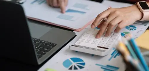 kobieta obliczająca na kalkulatorze, jaka jest minimalna kwota kredytu hipotecznego