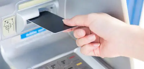 Kobieta wkłada kartę bankomatową do terminala