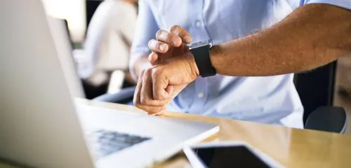 Mężczyzna pracuje na komputerze w biurze i sprawdza, która jest godzina