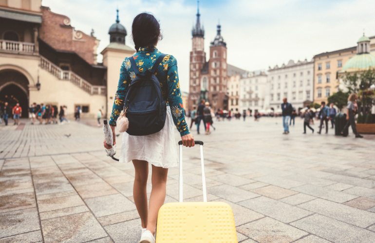 kobieta z walizką idąca przez Rynek Główny w Krakowie
