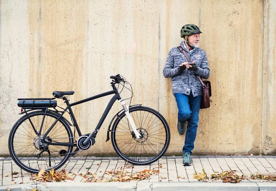 rowerzysta na chodniku z rowerem elektrycznym