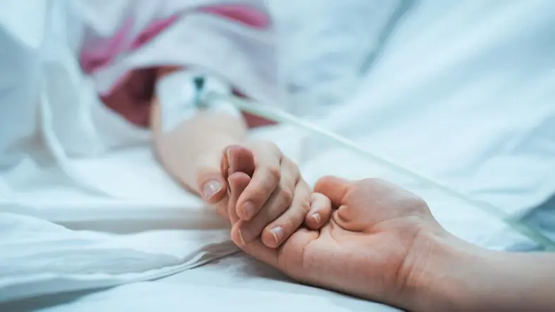 trzymanie za rękę osoby leżącej pod kroplówką w szpitalu