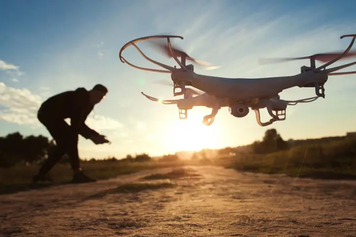 Mężczyzna steruje dronem podczas zachodu słońca
