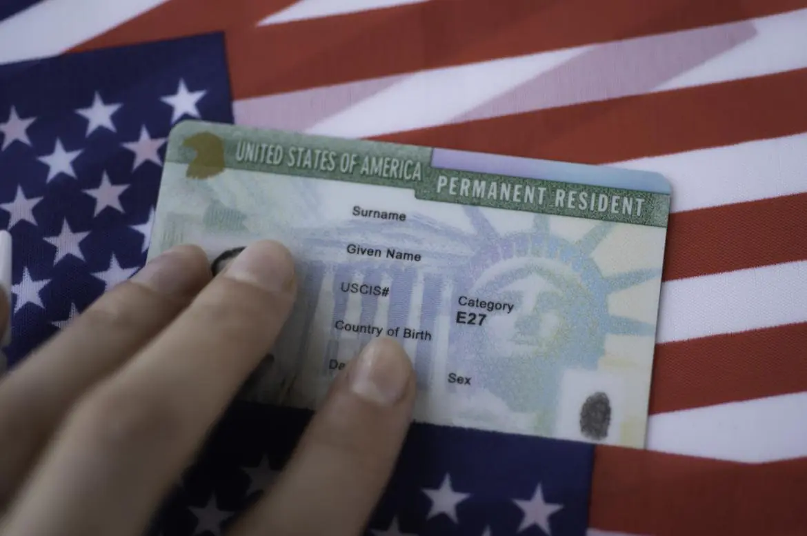 karta stałego pobytu w USA (zielona karta) na tle flagi Stanów Zjedoczonych