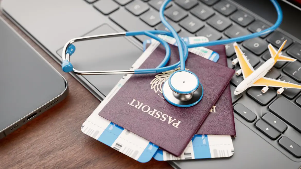 paszport, wizy leżące na klawiaturze laptopa, a na nich stetoskop