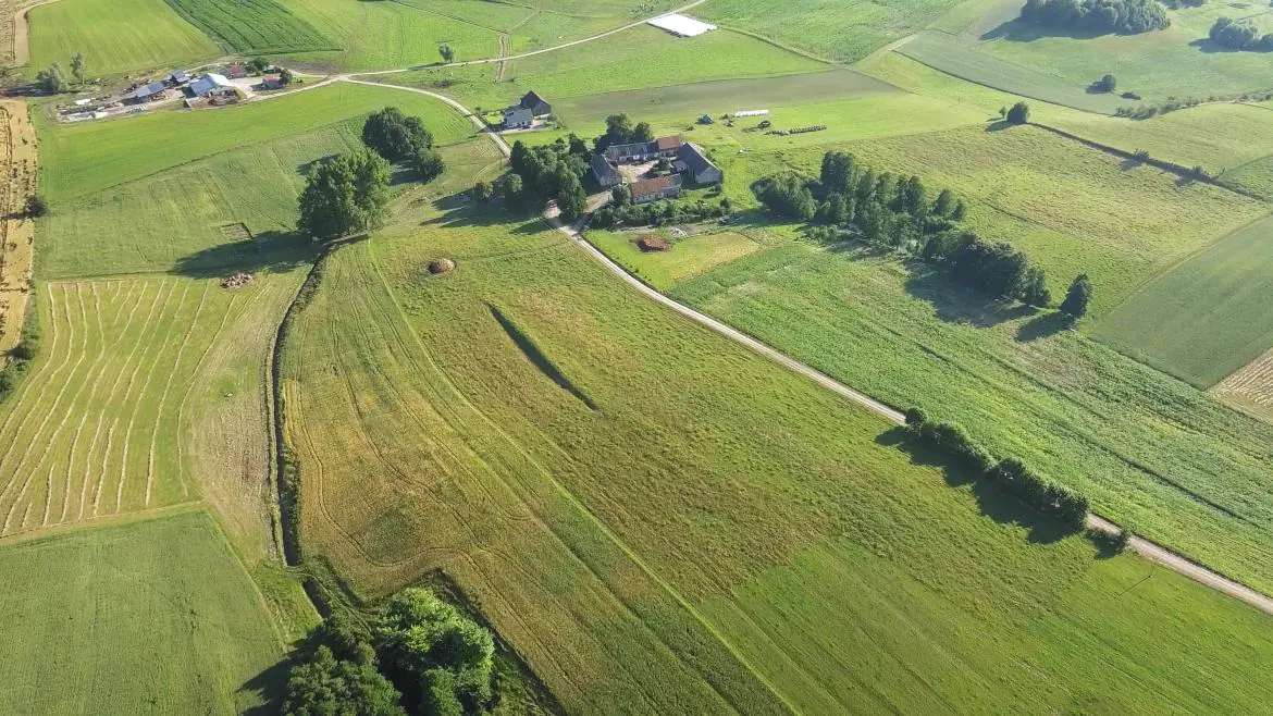 Widok z góry na ziemię działkę rolną z zabudowaniami