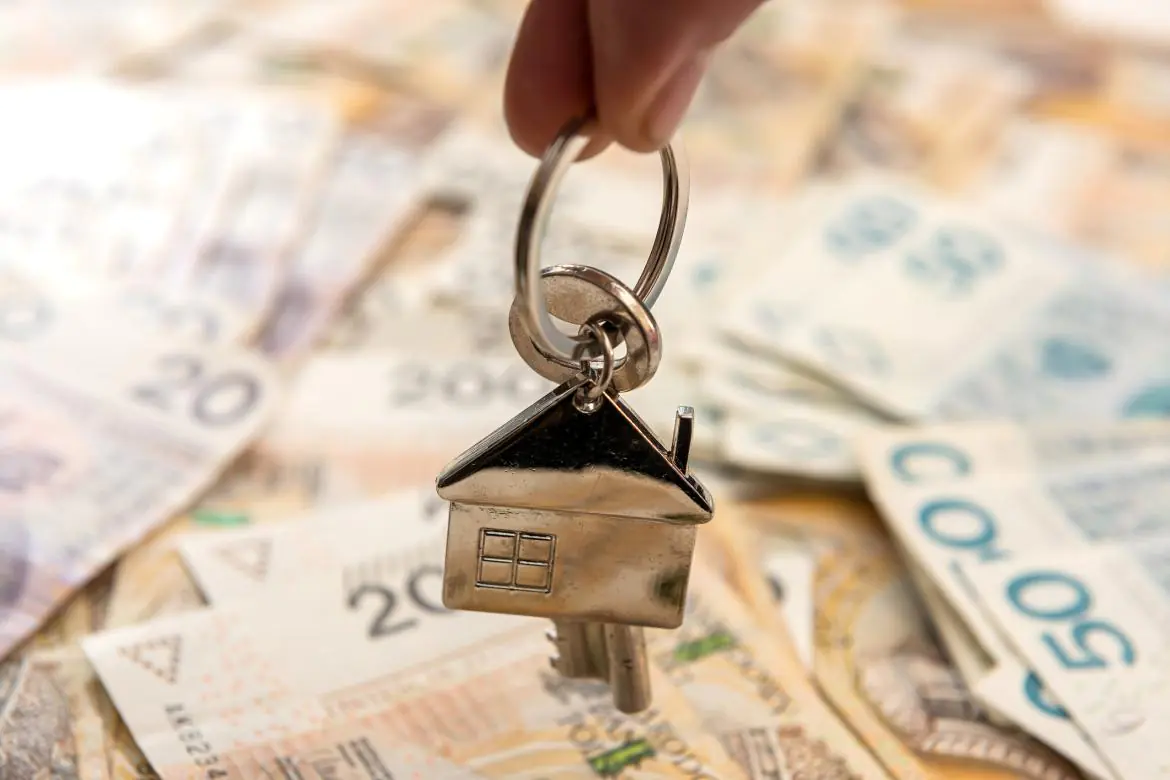 Brelok w kształcie domu na tle pieniędzy