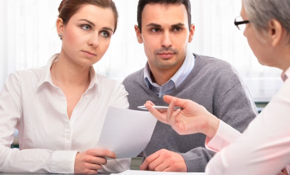 Młoda para podczas rozmowy z doradcą w biurze podróży, analizująca dokumenty i ofertę wycieczki. Opis rozszerzony (na stron