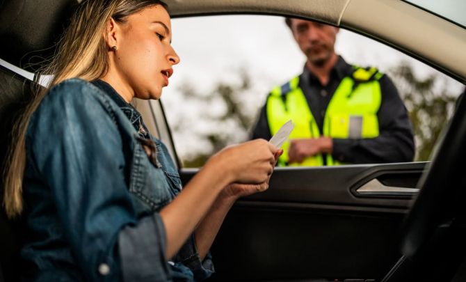 Kobieta w samochodzie i policjant sprawdzający jej dokumenty