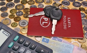 karta pojazdu i kluczyki do samochodu położone na polskich monetach