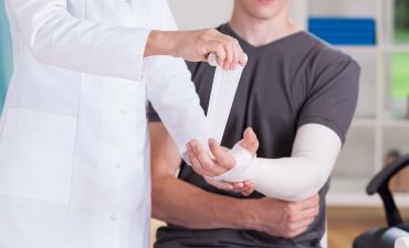 pielęgniarka owija pacjentowi złamaną rękę