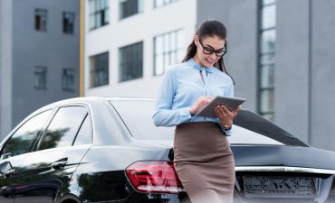 Kobieta stoi obok samochodu i sprawdza dokumenty