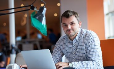 uśmiechnięty mężczyzna w biurze przed laptopem