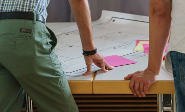 mężczyzna pochyla się nad biurkiem z dokumentami